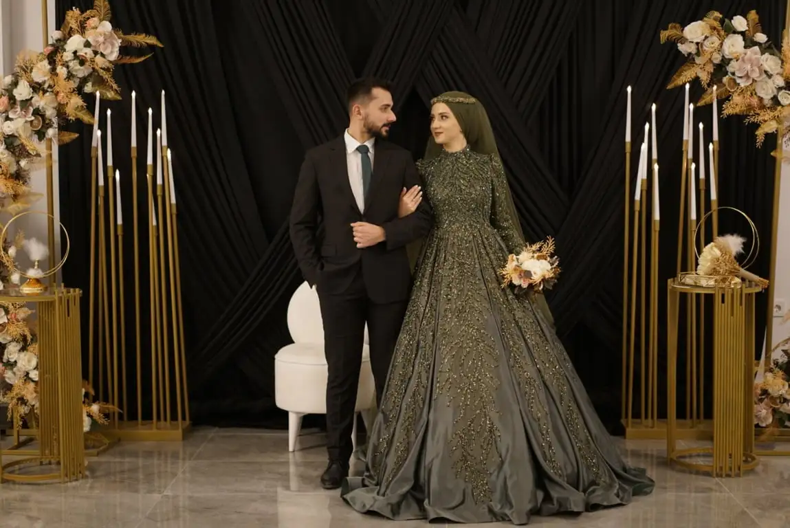 Gelin ve damat, siyah drapeli fonun önündeki çiçek kemerinde